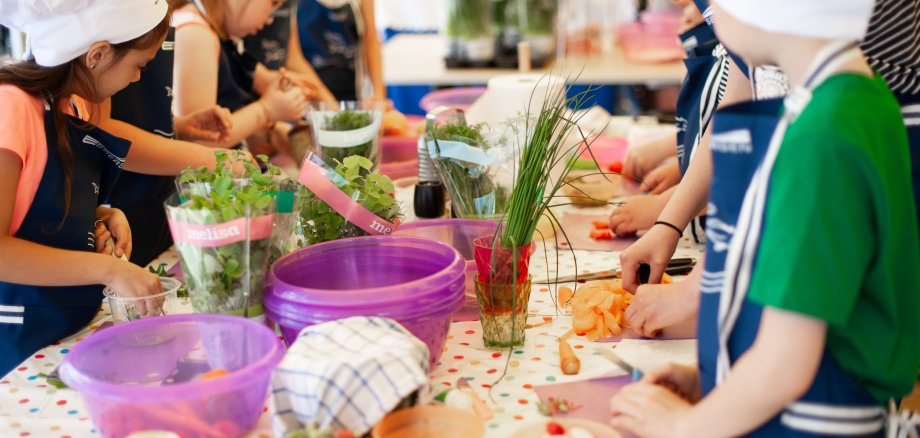 Mehrere Kinder mit Kochmütze kochen