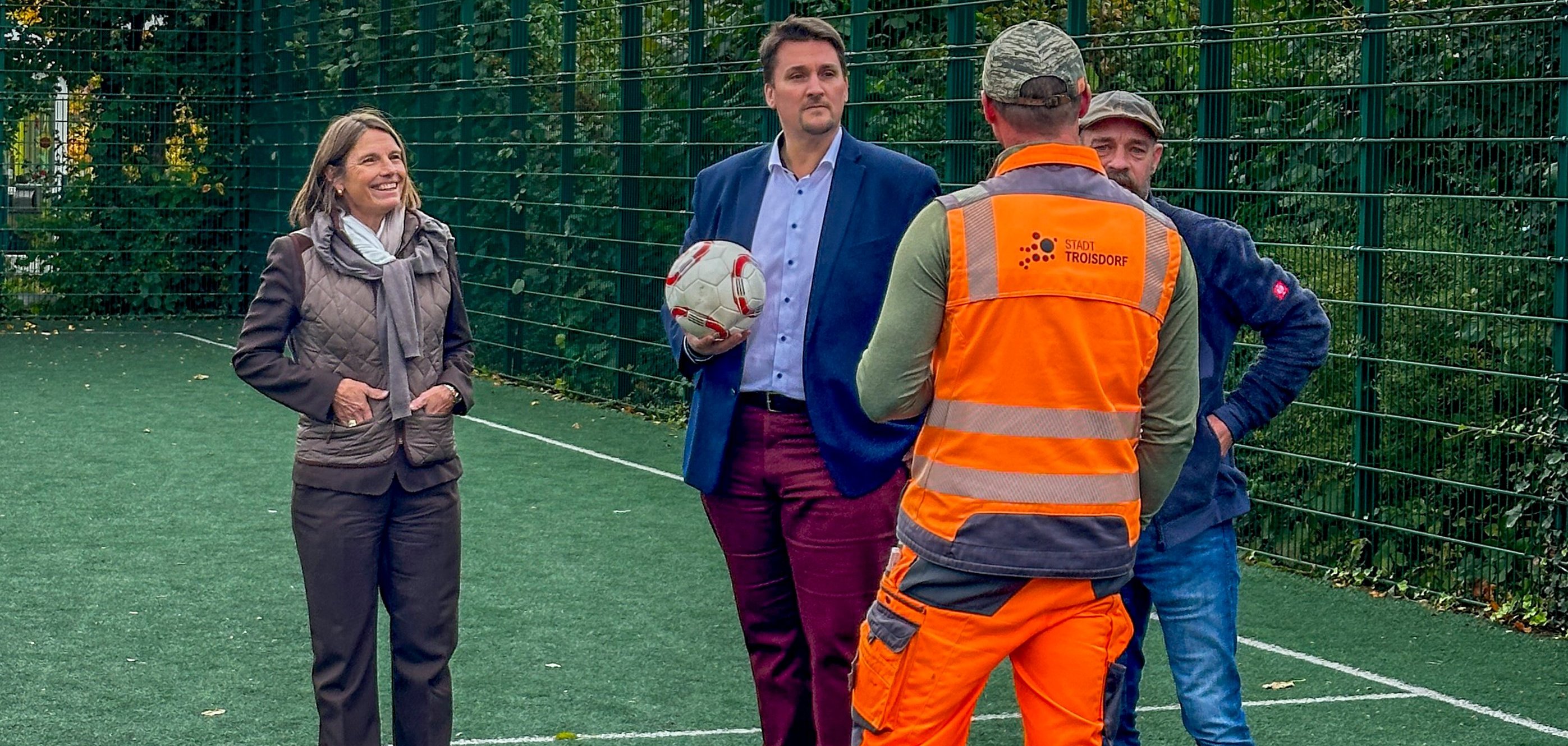 Bürgermeister Alexander Biber, die 1. Beigeordnete Tanja Gaspers und Mitarbeitende des Bauhofs inspizieren den Bolzplatz an der Maarstraße in Spich.
