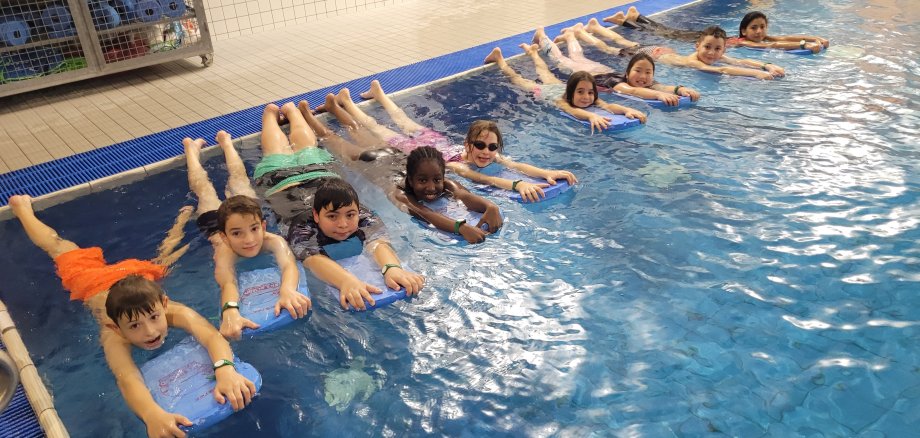 Kinder mit Schwimmbrett im Hallenbad