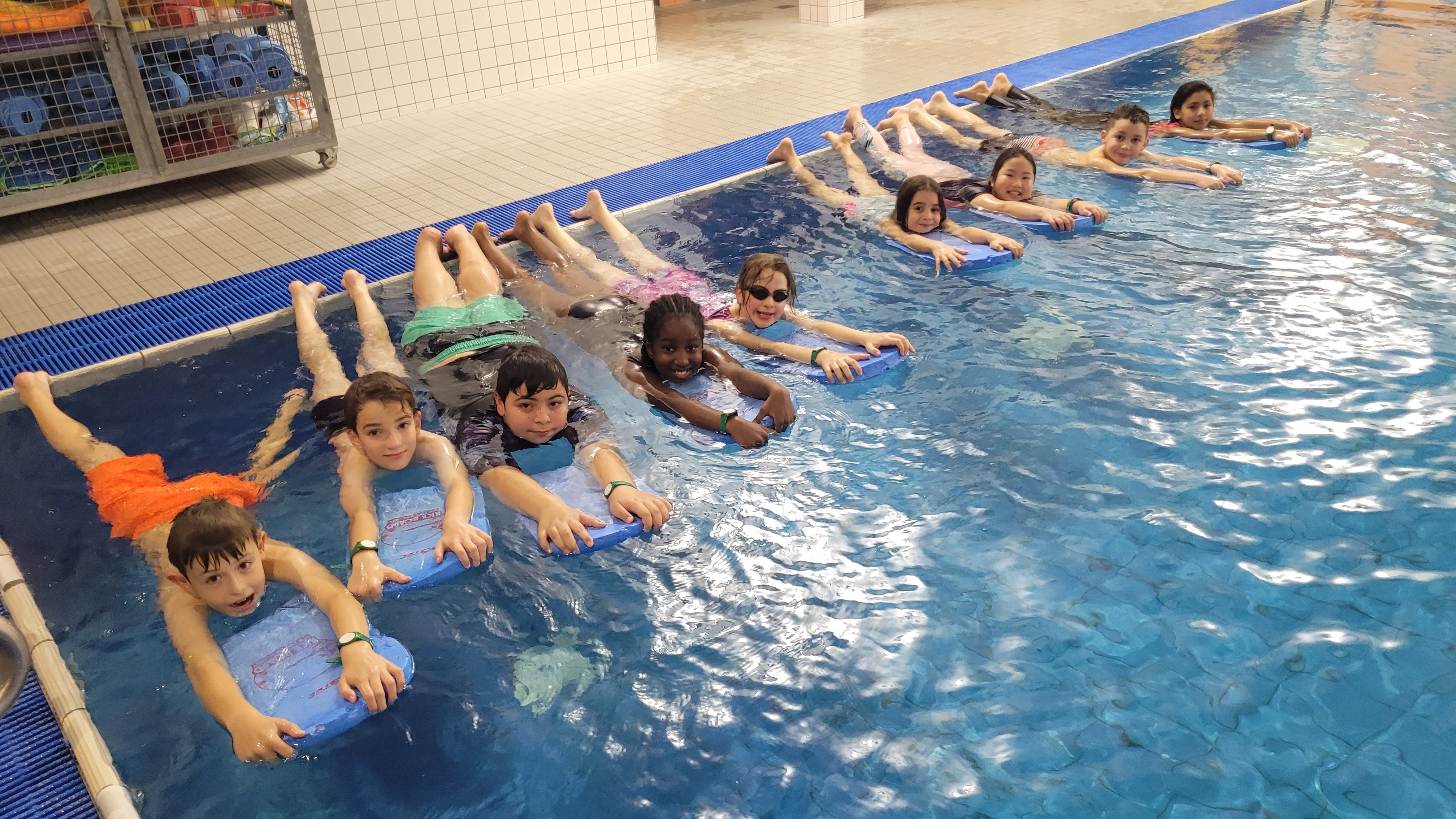 Kinder mit Schwimmbrett im Hallenbad