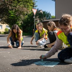 Im Rahmen des Termins gestalteten die Schulkinder die Wege von der Hol- und Bringzone zur Schule mit gelber Sprühfarbe („gelbe Füße“) und bunter Kreide.