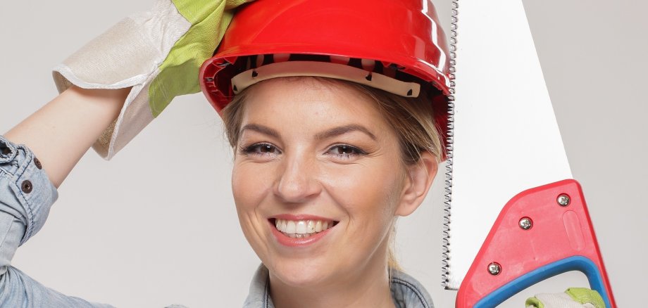Frau mit Bauhelm und Säge