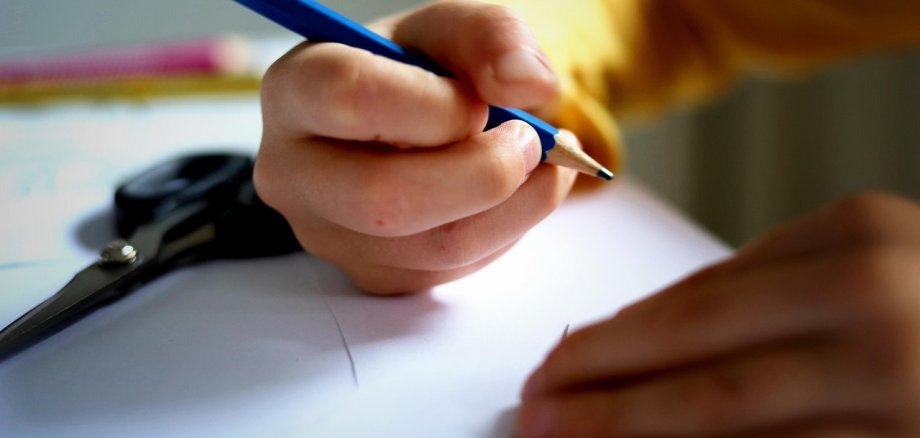 Kinderhand schreibt mit Bleistift