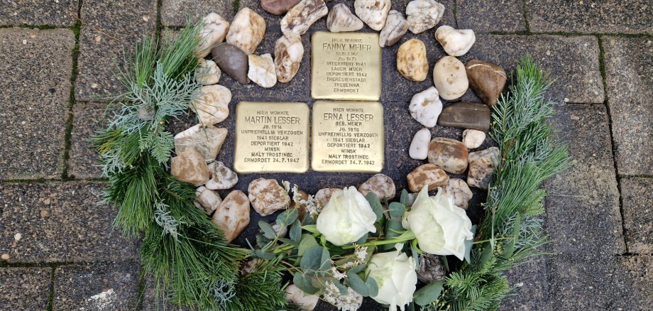 Die drei Stolpersteine, dekoriert mit Steinen und einem Tannenkranz