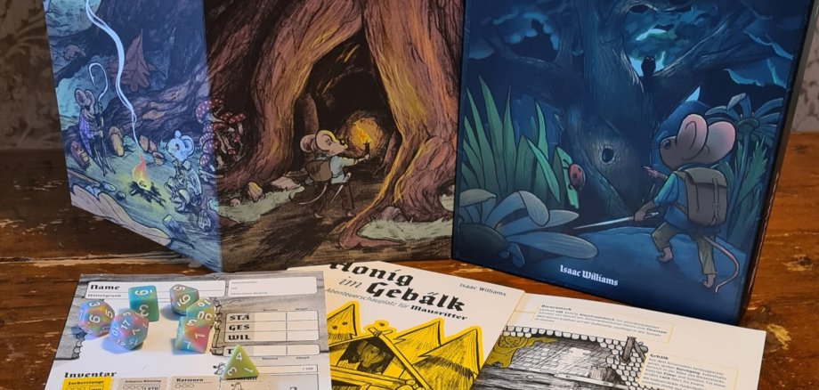 Das Bild zeigt Spielmaterial des Rollenspiels „Mausritter“: Regelbuch mit Maus-Illustration, Spielschirm, Würfel, Charakterbogen und Abenteuerkarten auf einem Holztisch ausgelegt.