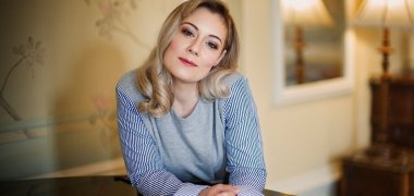 Auf dem Bild ist Angela Simkin zu sehen, sitzend an einem Klavier Auf dem Bild ist Angela Simkin zu sehen, sitzend an einem Klavier