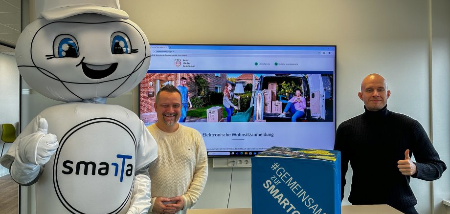 Smart City Maskottchen smarTa, Jan Masemann (Amtsleiter Standes- und Bürgeramt), Sebastian Glees (Projektleiter)