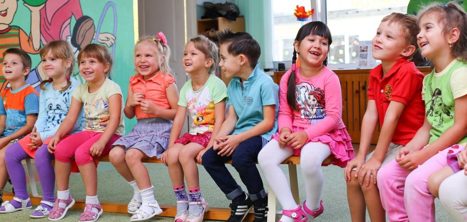 Kinder sitzen nebeneinander in der Kita