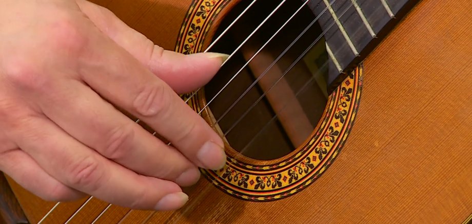Eine Hand an einer Akkustik-Gitarre