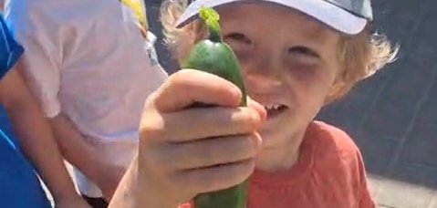 Ein Kind mit einer Gurke in der Hand