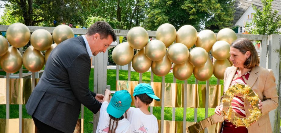 Bürgermeister Alexander Biber und die Erste Beigeordnete Tanja Gaspers mit Kindern vor dem Tor