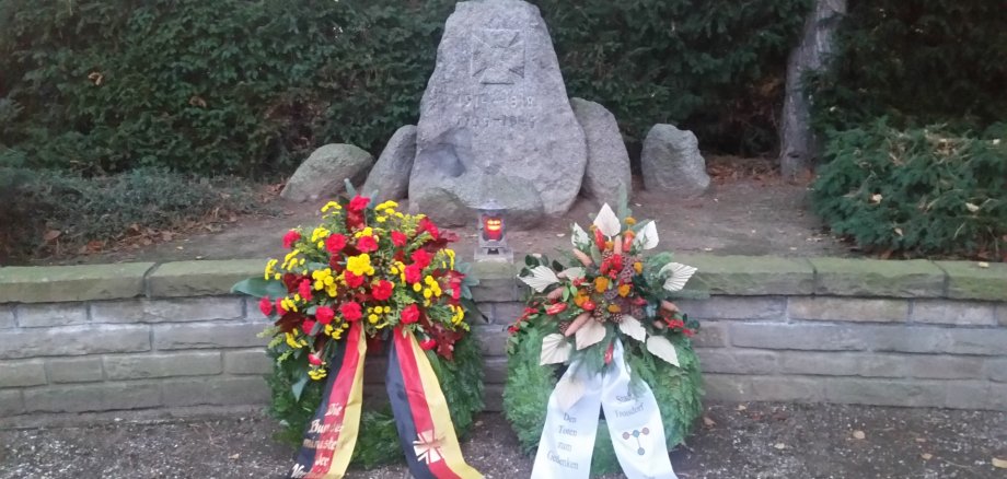 Kränze vor einem Gedenkstein