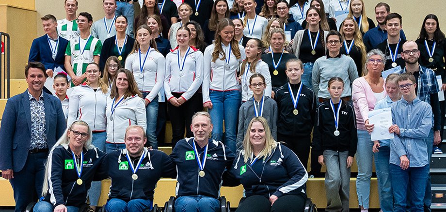Behinderte und Nicht-Behinderte Sporteler*innen beim Gruppenfoto in einer Sporthalle
