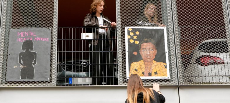 Schülerinnen befestigen Plakat-Kunst an  Parkhaus
