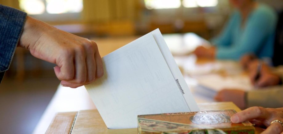 Stimmzettel wird in Wahlurne geworfen