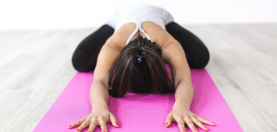 Eine Frau auf rosa Matte beim Yoga