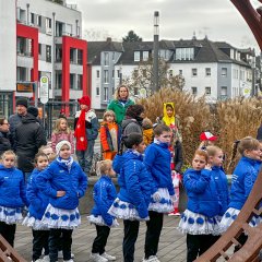 Mädchen mit weißen Kleidern und blauen Jacken warten vor dem Rathaus