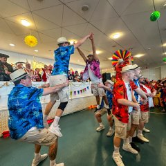In Shorts und Hawaii-Hemd verkleidete führen eine Tanzaufführung vor