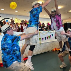 In Shorts und Hawaii-Hemd verkleidete führen eine Tanzaufführung vor