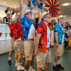 In Shorts und Hawaii-Hemd verkleidete führen eine Tanzaufführung vor