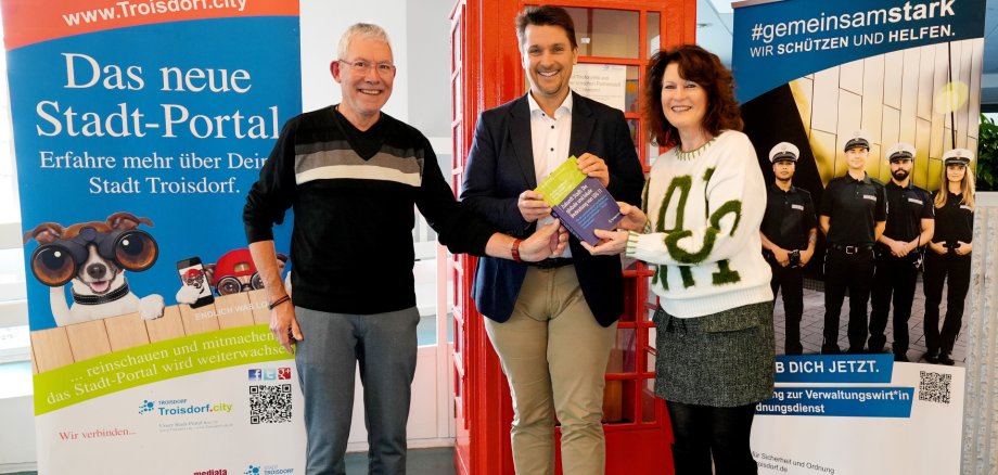Gruppenfoto: Drei Personen präsentieren ein Buch. Bürgermeister Biber neben Bernhard Schröder und Helga Berg