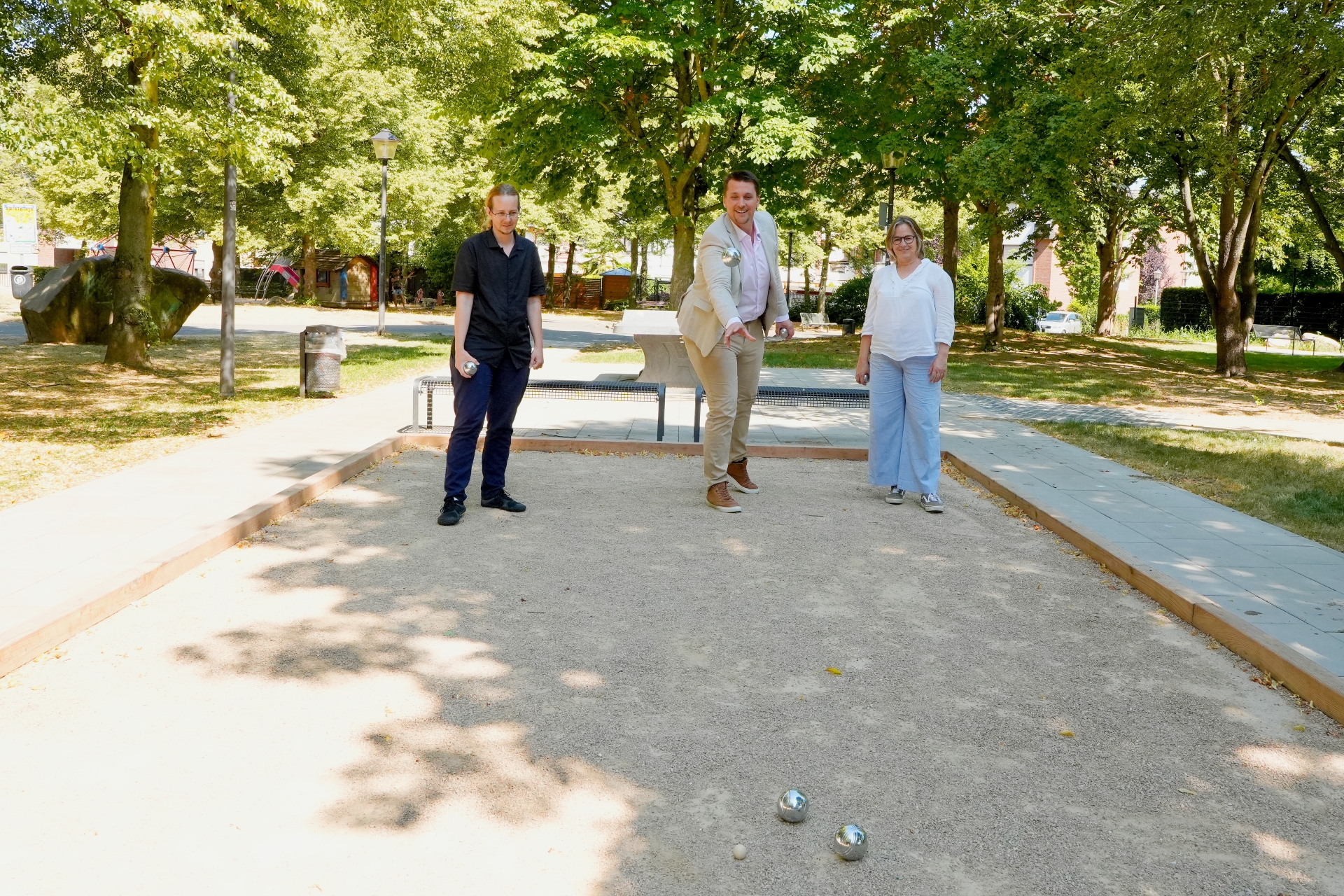 Zwei Männer rund eine Frau auf einem Bouleplatz
