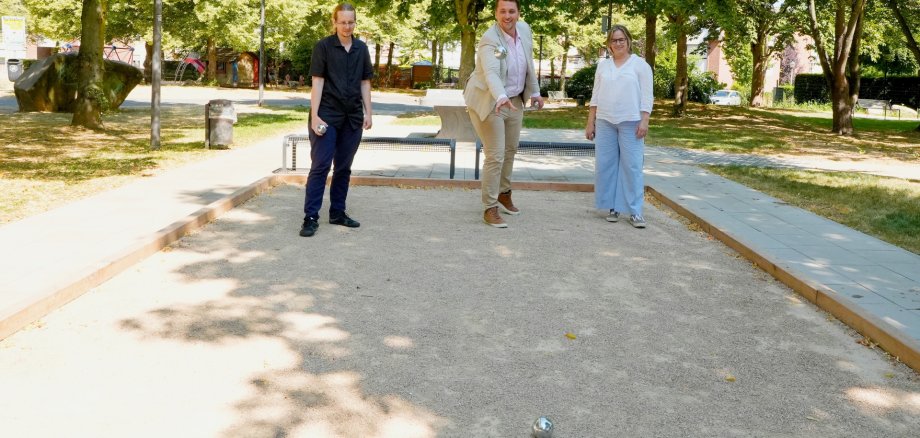 Zwei Männer rund eine Frau auf einem Bouleplatz