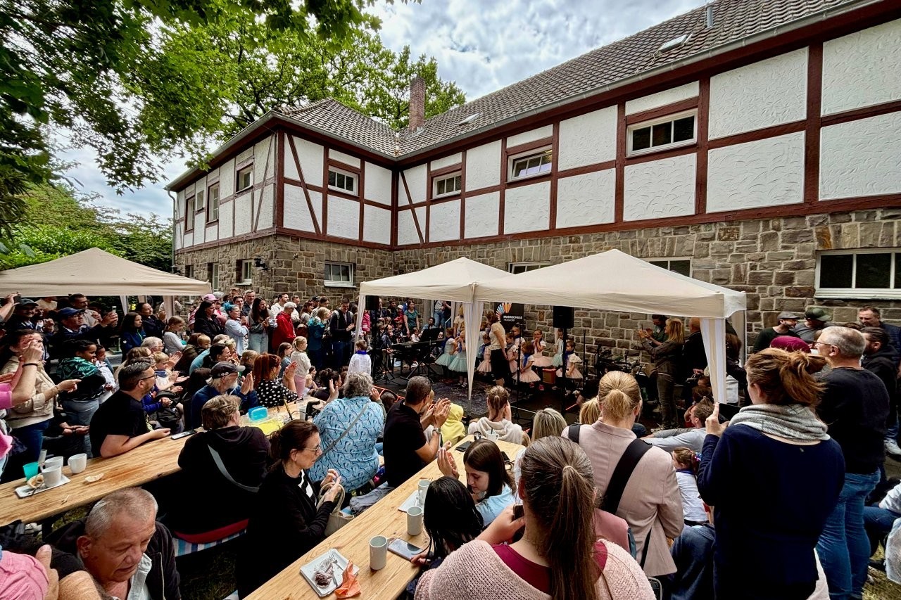 Viele Besucherinnen und Besucher verfolgen eine Aufführung beim Tag der offenen Tür vor dem Gebäude der Musikschule Troisdorf.