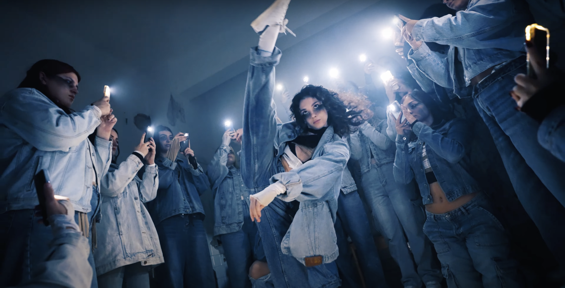 Mehrere Menschen nehmen an einem kreativen Tanzfilm-Workshop im Kunsthaus Troisdorf teil. Sie bewegen sich frei im Raum, einige filmen sich gegenseitig mit Kameras oder Smartphones, während andere gemeinsam an Choreografien arbeiten.