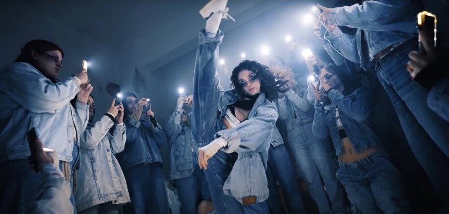 Mehrere Menschen nehmen an einem kreativen Tanzfilm-Workshop im Kunsthaus Troisdorf teil. Sie bewegen sich frei im Raum, einige filmen sich gegenseitig mit Kameras oder Smartphones, während andere gemeinsam an Choreografien arbeiten.