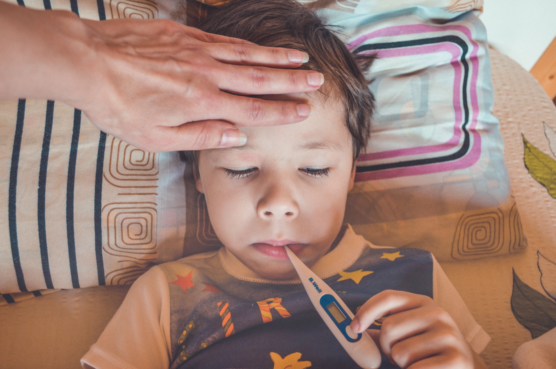 Kranker Junge im Bett mit Fieberthermometer