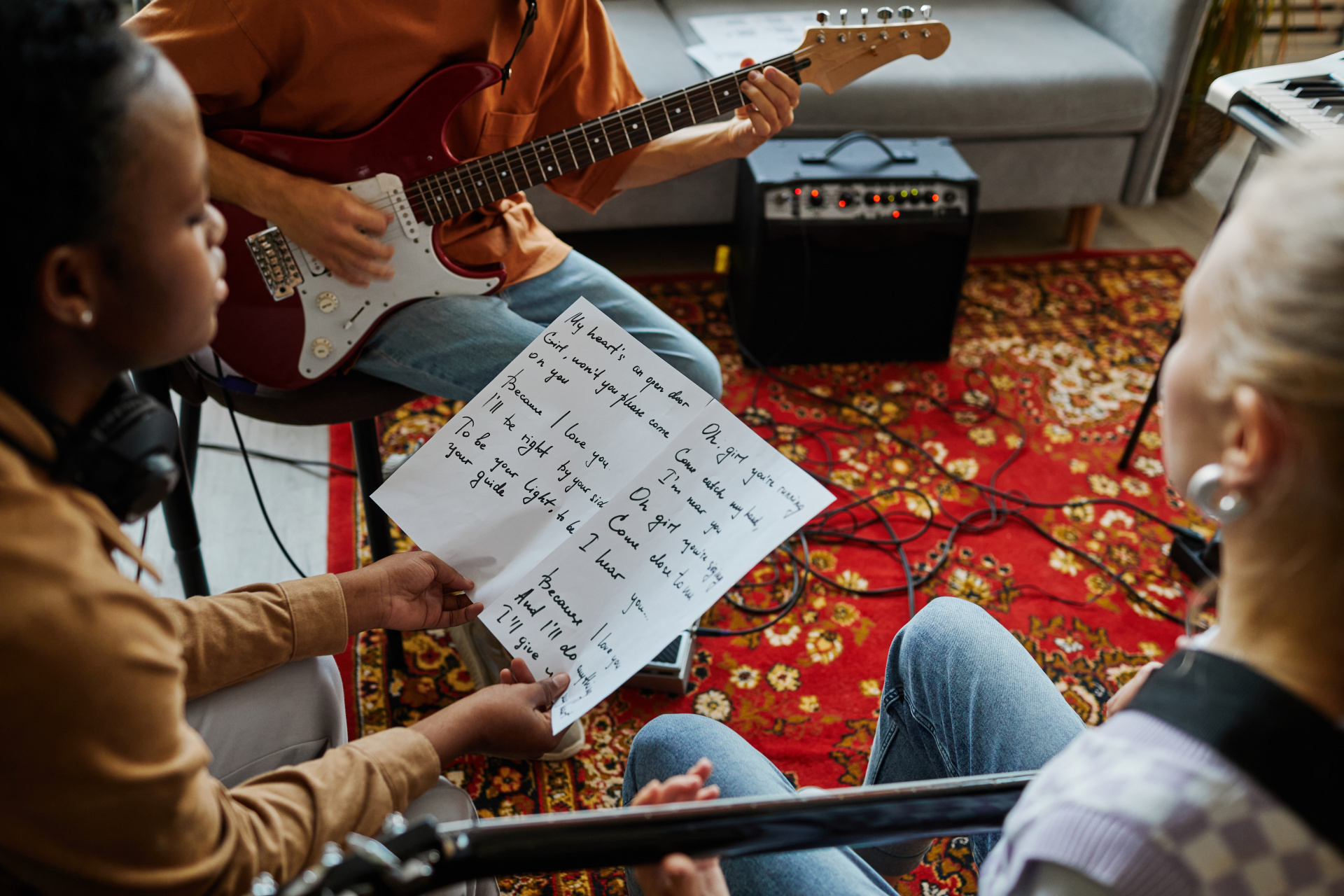 Nahaufnahme einer jungen Frau, die gemeinsam mit einer Musikband Songs schreibt und ein Blatt mit Liedtexten hält