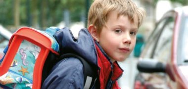 Junge auf dem Schulweg am Straßenrand